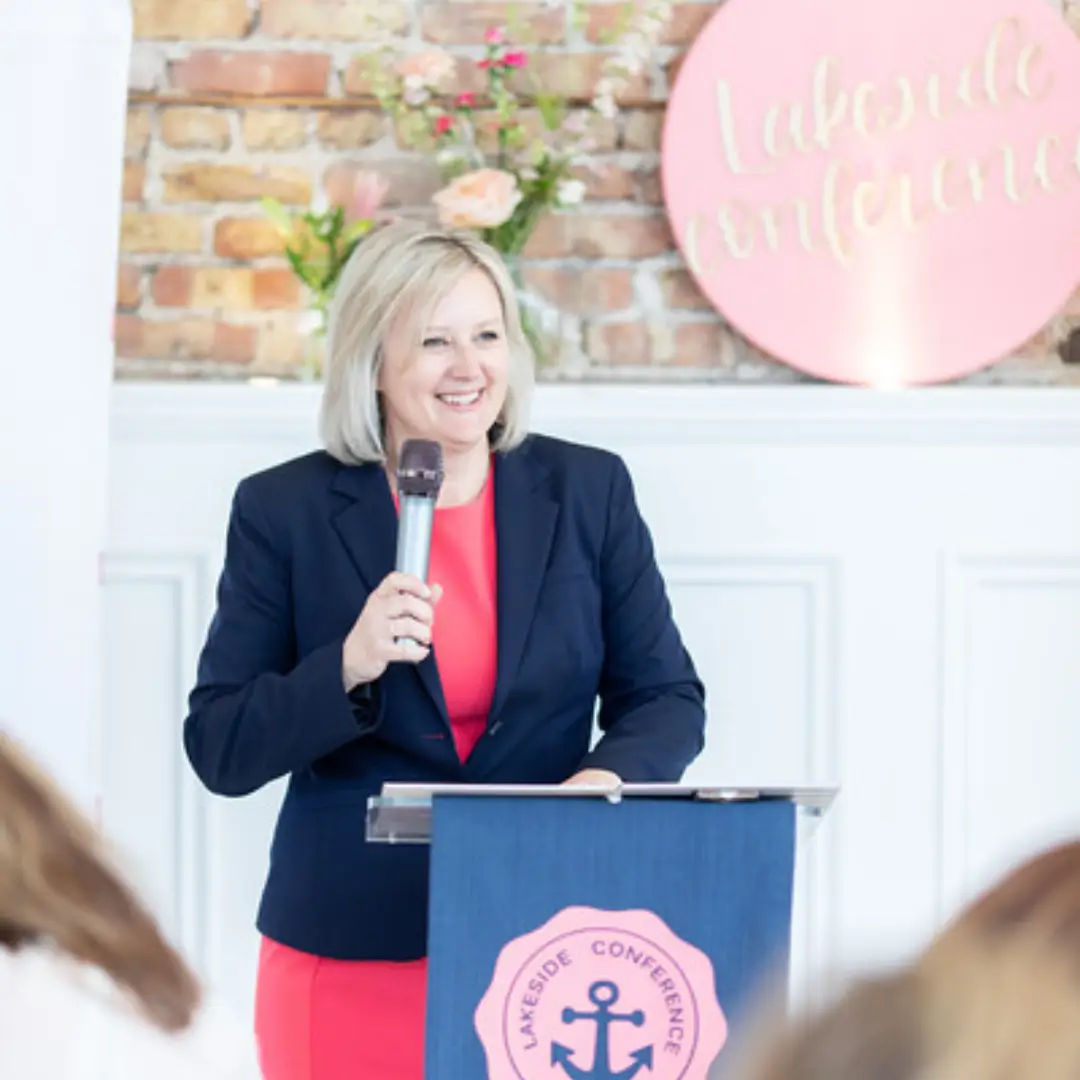 Robin speaking in front of podium holding a microphone